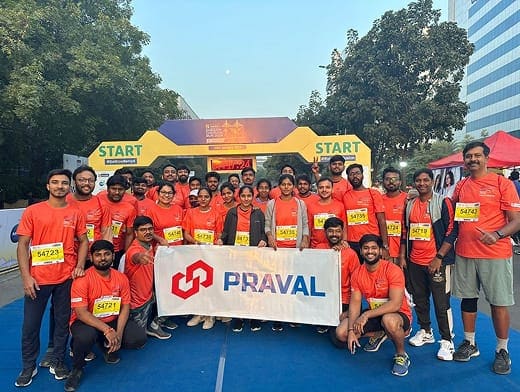 Praval runners in matching orange T-shirts at the start line, holding a Praval banner